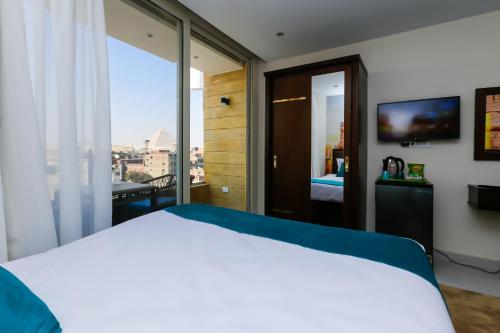 a bedroom with a white bed and a large window at Diamond Pyramids View Inn in Cairo