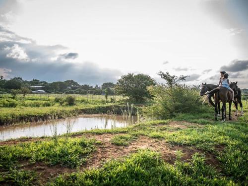 a woman riding a horse next to a river at The Barn at Tembele in Dalmada AH