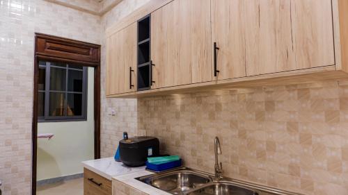 a kitchen with a sink and wooden cabinets at Opheboat Villa and Cuisine Services in Accra