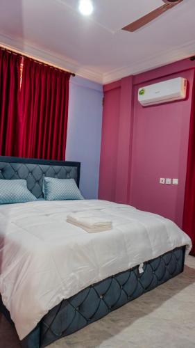 a bedroom with a large bed with pink and purple walls at Opheboat Villa and Cuisine Services in Accra