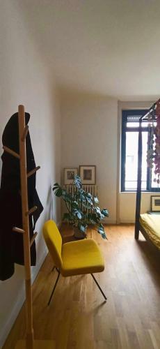 un salon avec une chaise jaune et une plante dans l'établissement 2 chambres chez l'habitant dans maison avec jardin SDB partagée, à Lorient