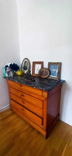 - une commode en bois avec des photos au-dessus dans l'établissement 2 chambres chez l'habitant dans maison avec jardin SDB partagée, à Lorient