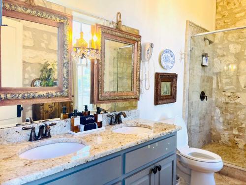 un bagno con due lavandini, un water e una doccia di Shopkeeper's Inn a Fredericksburg