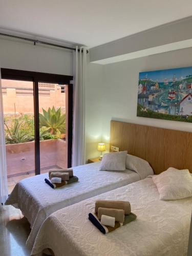 two beds in a bedroom with a large window at Oasis Coto Real apartments in San Luis de Sabinillas