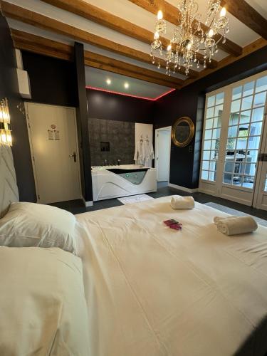 Cette chambre comprend un grand lit blanc et un lustre. dans l'établissement G7 Loft SPA & Terrasse centre Angouleme, à Angoulême
