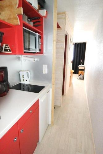 une cuisine avec un évier et des placards rouges ainsi qu'un couloir dans l'établissement Résidence Le France - Studio 3/4 pers - LE FRANCE - PLAGNE CENTRE MAE-1784, à Aime La Plagne
