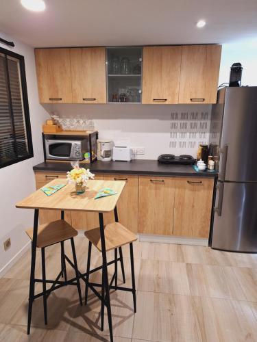 une cuisine avec une table et un réfrigérateur en acier inoxydable dans l'établissement Joli studio 25m2 avec cuisine, à Chantemerle-sur-la-Soie