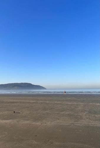 a person walking on a beach near the ocean at Cosmopolitan Praia Flat in Santos