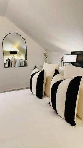 a bed with black and white pillows and a mirror at St Mary's Mews in Truro