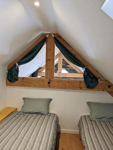 une chambre mansardée avec deux lits et une fenêtre dans l'établissement Gîte Le Cerbillona- Gavarnie, France, à Gavarnie