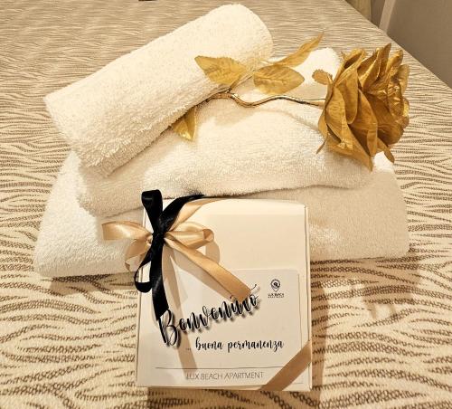 a couple of towels and a sign on a bed at Lux Beach Apartment GOLD in Lido di Ostia
