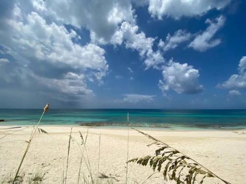 a sandy beach with the ocean and clouds in the sky at Beach'nBarefoot (Love Beach) - nestled on the beach in Orange Hill