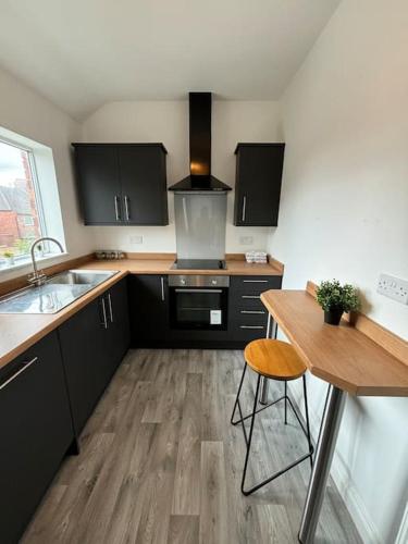 a kitchen with black cabinets and a wooden floor at 2 Bed Flat Wallsend in Willington Quay