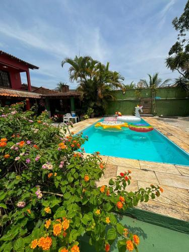 a swimming pool in a backyard with flowers in the foreground at Hostel Casa Jambo Guaruja in Guarujá