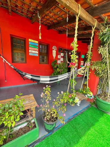 a red house with a hammock and some plants at Hostel Casa Jambo Guaruja in Guarujá