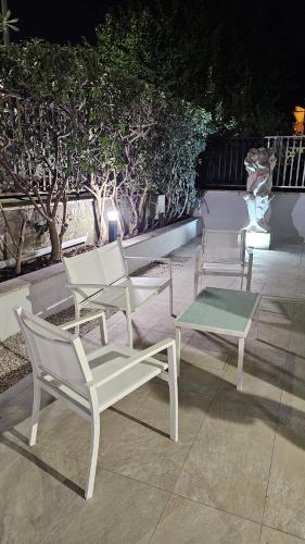 three white chairs and a table on a patio at Lux Beach Apartment GOLD in Lido di Ostia