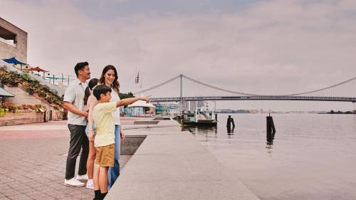 a family standing next to a river with a bridge at Loews Philadelphia Hotel in Philadelphia