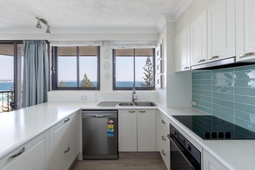 a kitchen with white cabinets and a sink at Columbia Beachfront Apartments on Rainbow Bay in Gold Coast