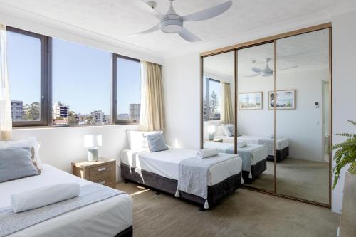 a hotel room with two beds and a mirror at Columbia Beachfront Apartments on Rainbow Bay in Gold Coast