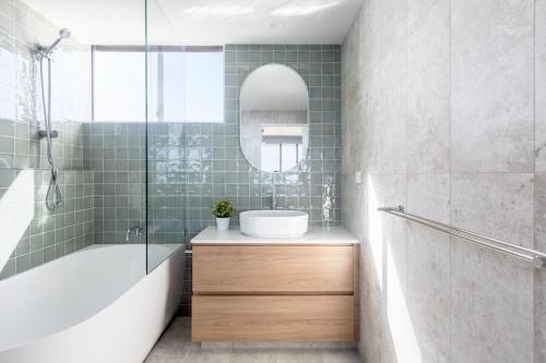 a bathroom with a tub and a sink and a mirror at Columbia Beachfront Apartments on Rainbow Bay in Gold Coast