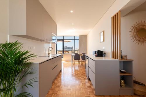 a kitchen with white cabinets and a large window at DoisPontoZero Júlio Dinis Gold in Porto