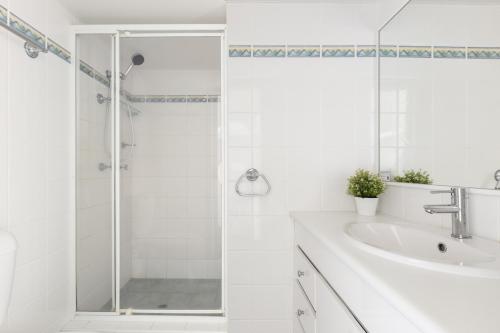 a white bathroom with a shower and a sink at Columbia Beachfront Apartments on Rainbow Bay in Gold Coast