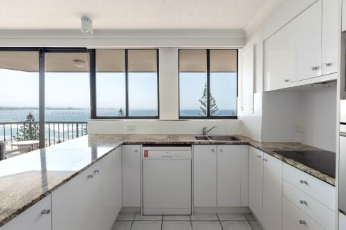 a kitchen with white cabinets and a view of the ocean at Columbia Beachfront Apartments on Rainbow Bay in Gold Coast
