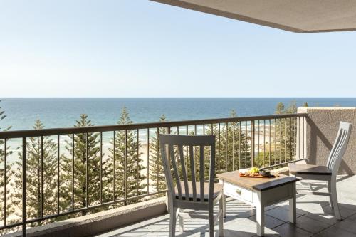 a balcony with two chairs and a table and the ocean at Columbia Beachfront Apartments on Rainbow Bay in Gold Coast