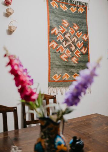 een vaas met bloemen op een tafel met een kleed bij CASA GUIVÁ in Oaxaca City
