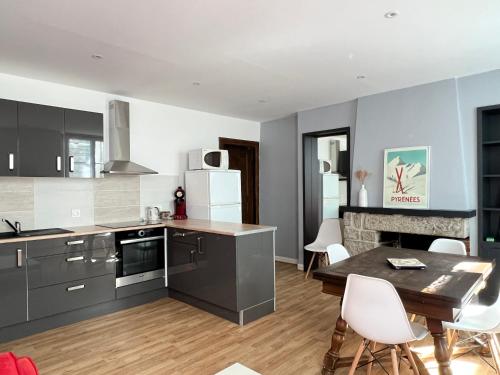 une cuisine avec des armoires grises et une table et des chaises dans l'établissement Au coeur de Cauterets, T2 + alcôve. 4P., à Cauterets
