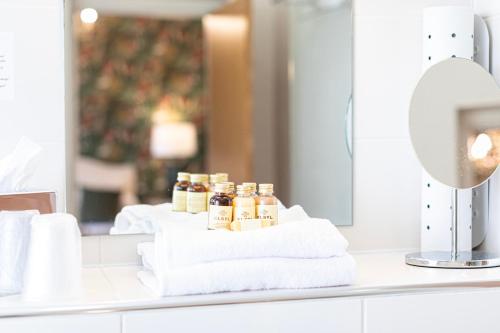 a bathroom counter with towels and a mirror at Roomours Hotel with Private Car Park in Llandudno