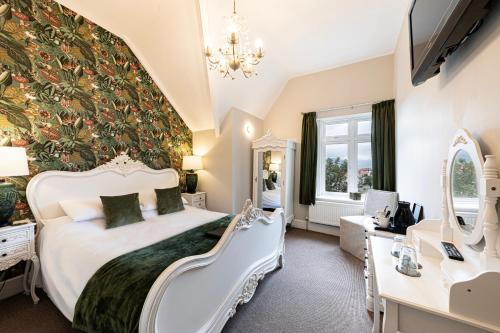a bedroom with a large white bed and a mirror at Roomours Hotel with Private Car Park in Llandudno