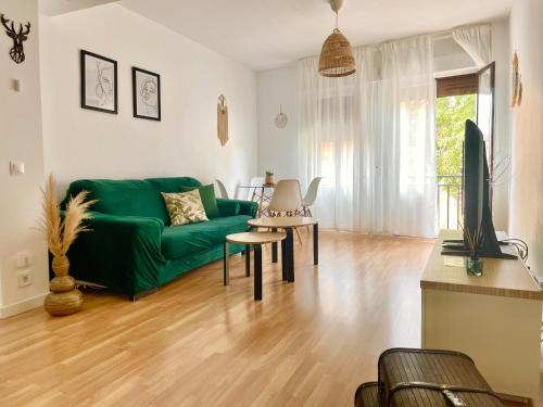 ein Wohnzimmer mit einem grünen Sofa und einem TV in der Unterkunft Apartamento Marcajada in Riaza