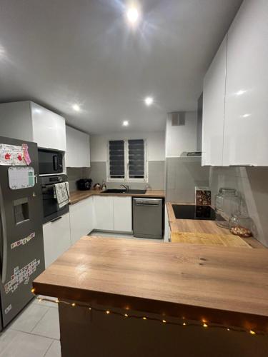 une cuisine avec des armoires blanches et un comptoir en bois dans l'établissement Jolie maison familiale, à Tourrettes