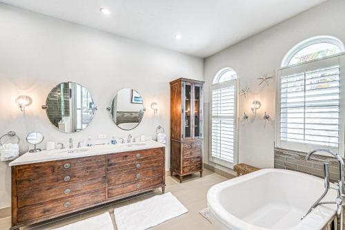 a bathroom with a tub and a sink and mirrors at Marco Island Home with Screened Pool Less Than 1 Mi to Beach in Marco Island
