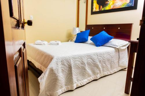 a bedroom with a bed with blue pillows on it at Hotel Arce Plaza in Valledupar