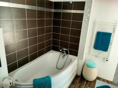 La salle de bains est pourvue d'une baignoire blanche et de serviettes bleues. dans l'établissement Un petit coin de campagne, à Beychac-et-Caillau