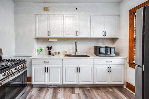 a white kitchen with a sink and a microwave at Amazing 3 bedroom home Steps, Airport, UofR, RIT, Strong in Rochester