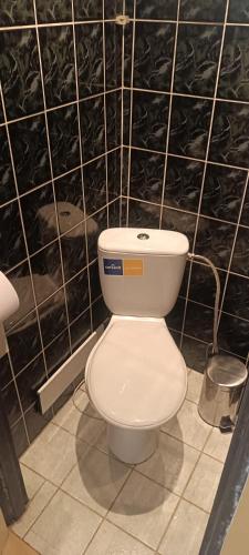 a white toilet in a black tiled bathroom at Orion in Mąchocice