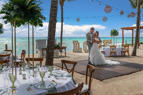 a bride and groom posing for a picture on the beach at El Beso Adults Only at Ocean Riviera Paradise All Inclusive in Playa del Carmen
