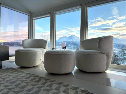 a bedroom with three chairs and a large window at EnUtsiktBalsfjord in Storsteinnes