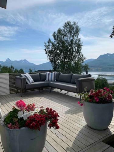 a couch sitting on top of a deck with flowers at EnUtsiktBalsfjord in Storsteinnes