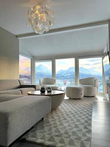 a living room with a couch and a table and windows at EnUtsiktBalsfjord in Storsteinnes