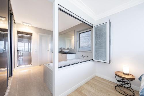 a white bathroom with a tub and a window at Ocean Sunset - Luxury Apartment with Ocean Views in Lancelin