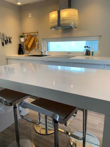 a kitchen with a large white counter with two bar stools at EnUtsiktBalsfjord in Storsteinnes