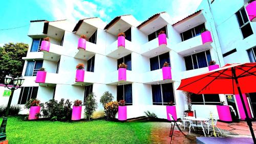 a large white building with pink windows and a red umbrella at Hotel Hacienda del Rio Oaxtepec in Pantitlán