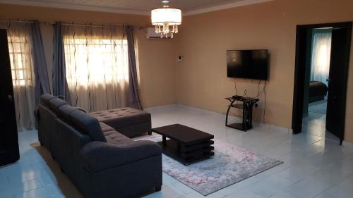 a living room with a couch and a tv at THE PALMS VILLA GRA Sagamu in Sagamu