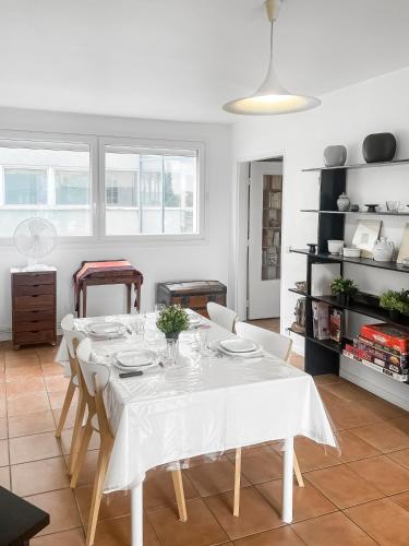 une salle à manger blanche avec une table et des chaises blanches dans l'établissement Confort et Style aux Portes de Paris, à Saint-Ouen