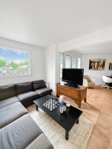 un salon avec un canapé et une télévision dans l'établissement Confort et Style aux Portes de Paris, à Saint-Ouen