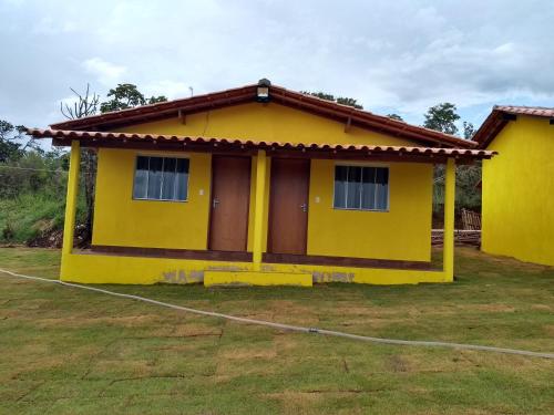 a yellow house in a yard at Pousada do Juninho in Capitólio